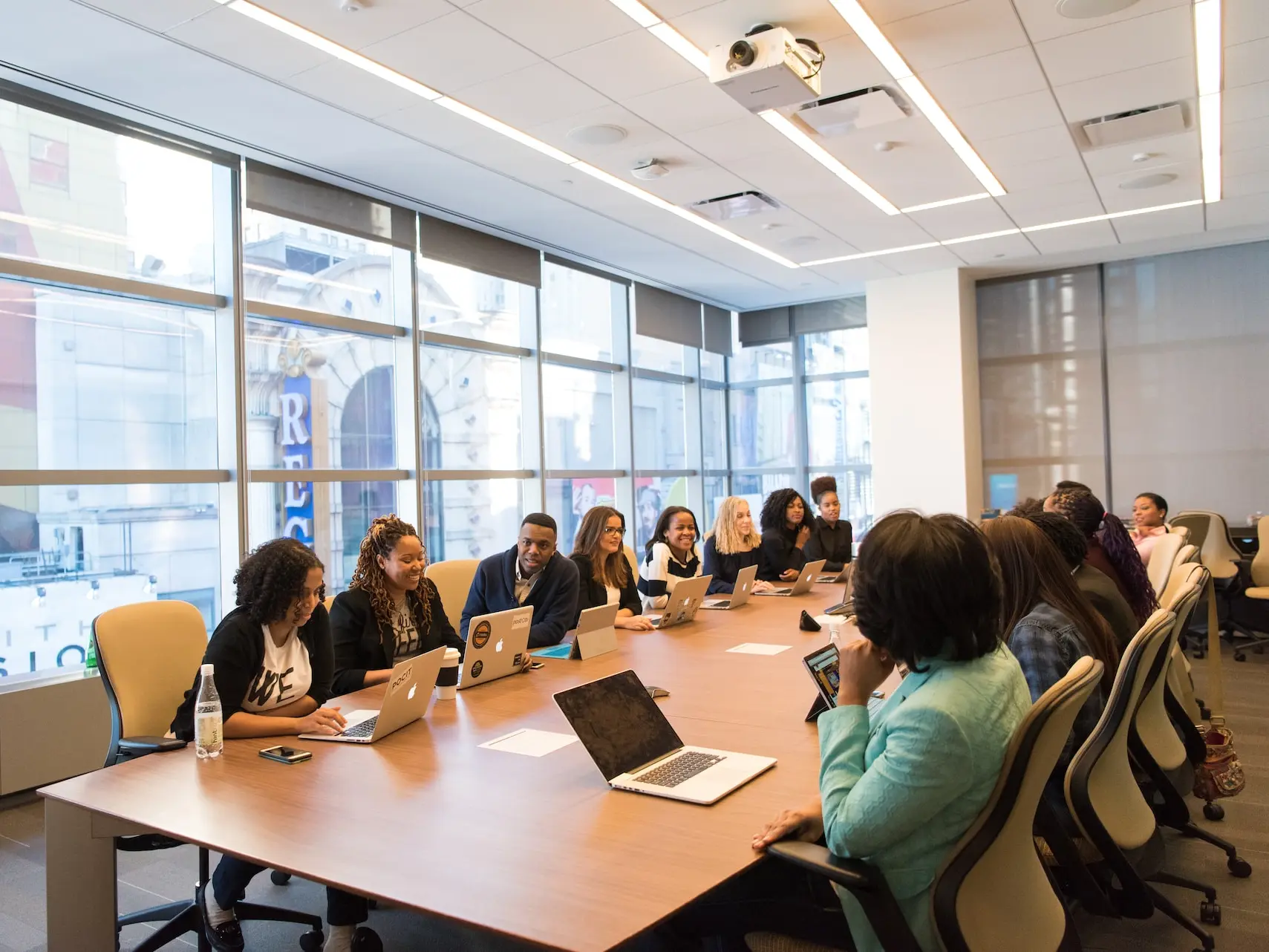 group of people sitting beside rectangular wooden table with laptops